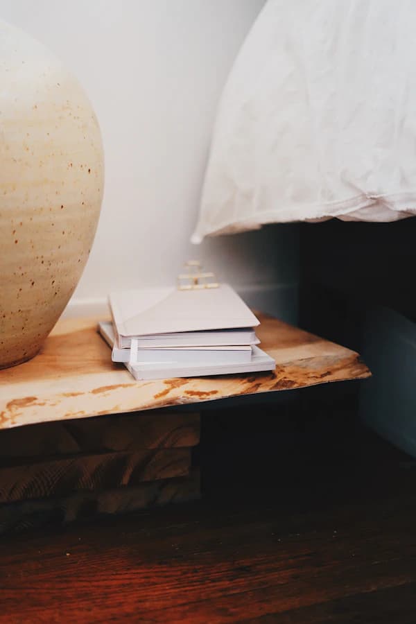 A stack of books beside a large ceramic vase on a wooden table.
