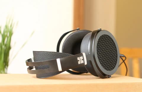 Black over-ear headphones resting on a sunlit wooden surface.